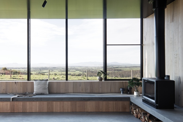 A bench seat lines the perimeter of the living area and the black formply ceiling reflects the colours of the surrounding landscape.
