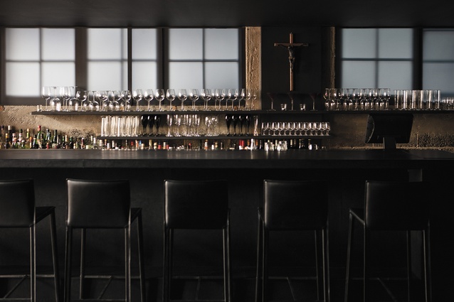The back bar, adjacent to the lounge area, is black-leather bound. A subtle glow from the translucent windows provides atmospheric light.