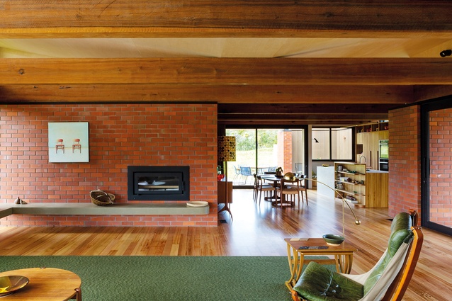 Brick cladding of the Whareora House runs from outside to in, creating a solid base for the horizontal roof beams.