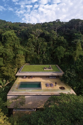 Constructed mostly from concrete and timber, the house features a green roof that blends into the trees when seen from above.