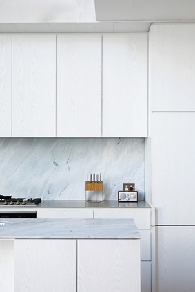 White cabinetry and marble-tiled benchtops contribute to a sharp yet warm palette in the kitchen.