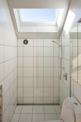 The all-white bathroom features a shower with a view of the sky. 