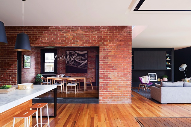 The dining room sits within the original red brick building envelope and is connected to the kitchen via a large opening. Artwork: Andrew Browne.
