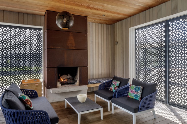 The outdoor room is clad in timber like an old bach, and features a Corten steel fireplace and metal filigree screening in a Moroccan pattern.