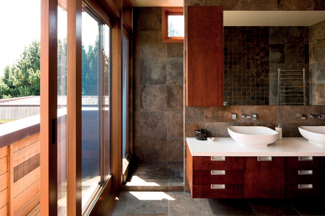 The bathroom is lined in natural stone with timber cabinetry.
