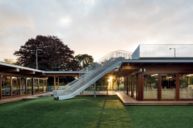 A rooftop playground provides pupils of Cathedral Grammar School with a slide down to a grass-laid courtyard below, in the middle of a new timber building. 