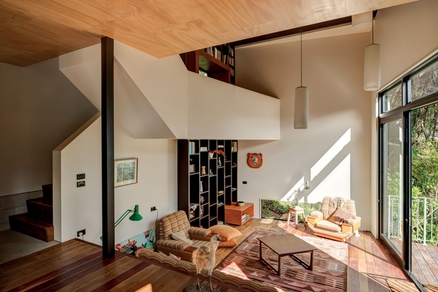 A mezzanine nook hangs in the middle of the double-height space above the living area.  