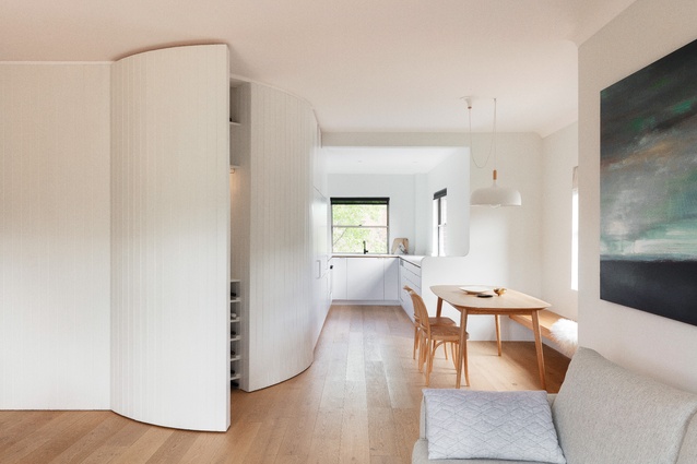 The insertion of a curved timber-panelled joinery wall defines the zones within the apartment, conceals original splayed walls and provides storage space. 