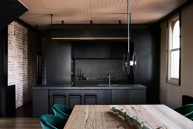 Fine perforated steel fixed to the kitchen's black joinery references the construction of the original building.