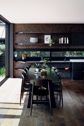 The kitchen and living room furniture is chosen to match the tones of the tiled wall. The kitchen table was custom made by Mckean Carnell, while the chairs were sourced from Backhouse.