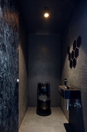 The black bathroom features mosaic hexagonal tiles and an Ikea hexagonal mirror. 