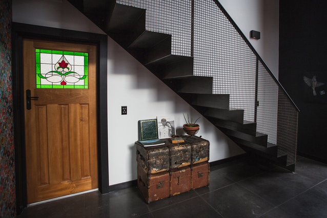 An old rimu door with stained glass panels is juxtaposed against the industrial look of the steel stair.