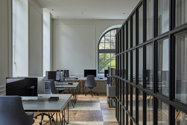 A Crittall window-styled room divider is used in the centre of the space as both a repetition of the window pane motif and as a solid subdivision of this space.