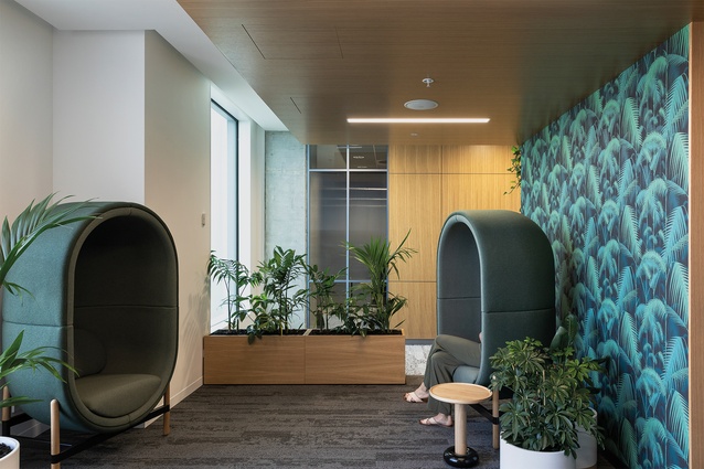 The wellness facility is furnished with capsule chairs by Kateryna Sokolova for Palau (supplied by Unison Workspaces) and its walls are lined with botanical wallpaper called Palm Jungle from Cole & Son.