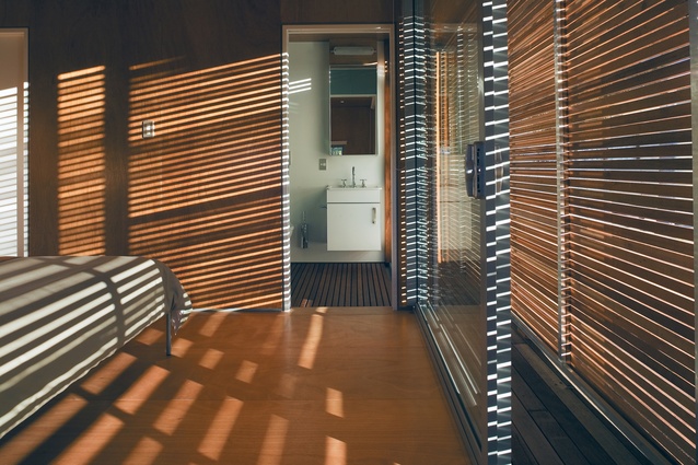 The main bedroom with its ensuite bathroom. The bedroom opens out on one side, via a sliding door protected by slatted timber screens, as do the bedroom and bunkroom at the opposite end of the bach.