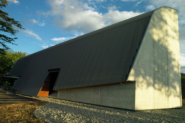 The main façade, framed in timber, floats lightly above the earth.