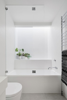 A stark, white bathroom reflects the house’s crisp palette and minimalist design language.

