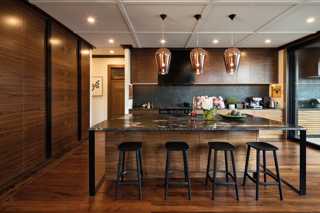 The large copper shades of the pendant lamps in this Westmere kitchen by Rogan Nash Architects add warmth and a reflective quality to this elegant design.
