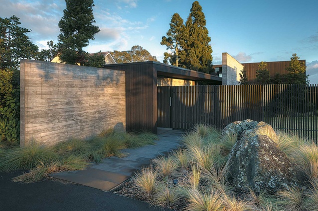 The vertical fins of the fence allow discreet glimpses of the house.