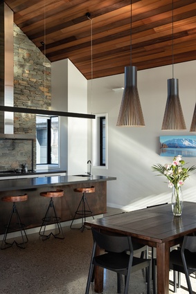The kitchen includes a Corten steel island front and a schist wall.