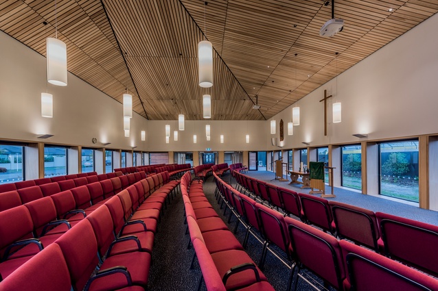 The worship hall features a dramatic timber ceiling and lantern-like lighting, hung low to create intimacy.