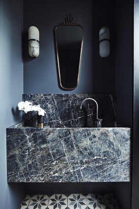 Opulent: The rich blue colour scheme of this small powder room in Killcare House by Decus Interiors on the central coast of New South Wales gives it a tasteful sense of opulence. A heavily veined marble vanity, patterned floor tiles and a vintage-style mirror simply add to its seductive appeal.