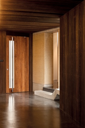 Rammed-earth House: The entrance foyer features a concrete stair that folds into a bench seat. 
