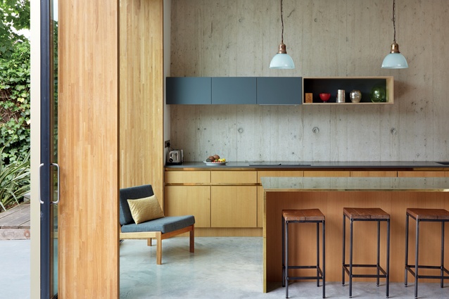 The kitchen’s minimal scheme allows the custom-made joinery, including the brass-clad island bench-top, to take centre stage.