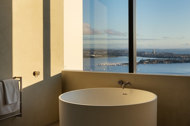 Walls in Marmorino limestone plaster and porcelain ceramic slabs on floors create a neutral backdrop for high-end bathroom fixtures and pristine bay views.