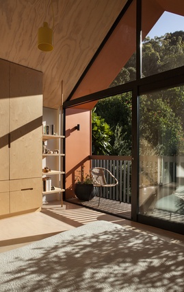Upstairs in the new 'pop-up' addition, a plywood-clad bedroom overlooks the garden.