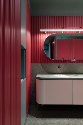 Recycled red metal rods line the bathrooms and are accented by a green terrazzo floor.