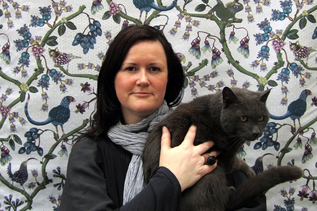 Genevieve Packer with Stinky the cat, in front of her Heads and Tails pattern fabric. 