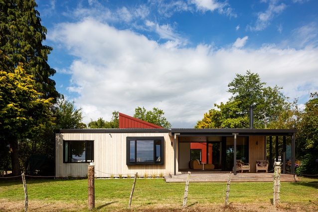 The lakeside view of the house references the original Lockwood bach, with a peep of the deep-red Colorsteel cladding beyond.