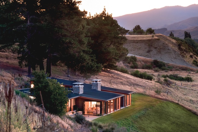 This holiday home near Wanaka steps down the hillside over three levels, with a floating roof plane that follows the contour of the slope.