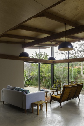 Lounge area of Pitoitoi House in Days Bay, Wellington. Exposed timber trusses allow for an elegant and cost-effective roof system.
