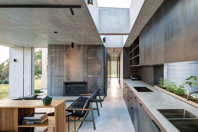 Above the kitchen, sharp voids and corners carved from concrete reveal views to the sky.