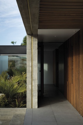 At the entrance, large-format Italian porcelain tiles from SCE and a cedar screen wall lead visitors to the front door.
