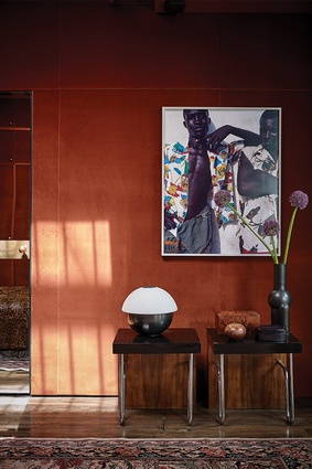 A photograph by Viviane Sassen hangs above a pair of matching console tables.