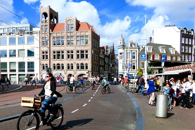 Pedal power in Amsterdam: dedicated cycleways encourage people to choose physical activity instead of opting for private cars, leading to greater health benefits and less pollution.