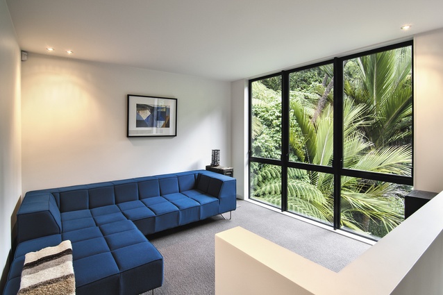 The sitting room enjoys green views through the floor-to-ceiling glazing.
