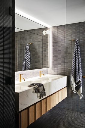 The juxtaposition of white marble and dark tiles lends the bathroom a quiet elegance.