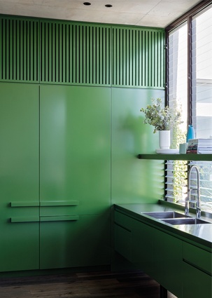 The kitchen’s glossy bright-green cabinetry visually connects it to the garden.