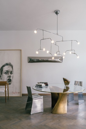 In the dining room, the Fireworks chandelier hangs above the bronze-based S-table and aluminium T-chairs.