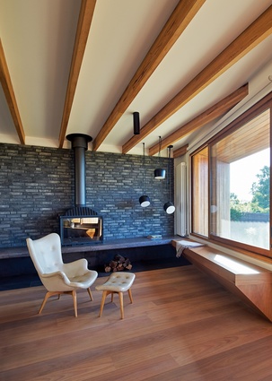 A dark brick wall behind the wood fireplace in the living room is a stunning focal point, but also works to store heat.