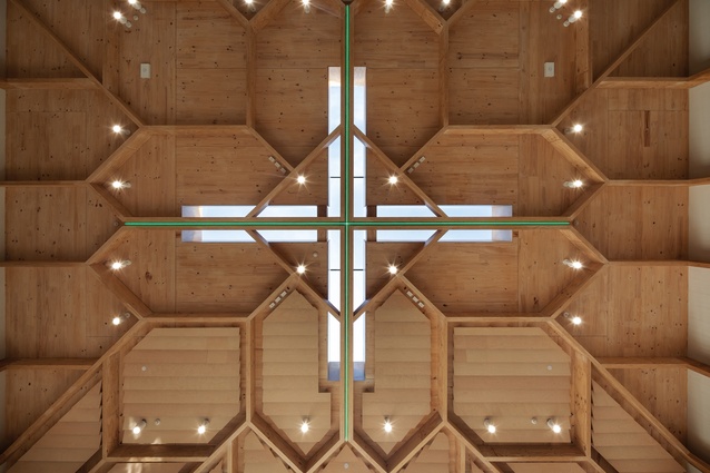 The timber vault of the auditorium with cruciform skylight and illuminated cross in the centre.