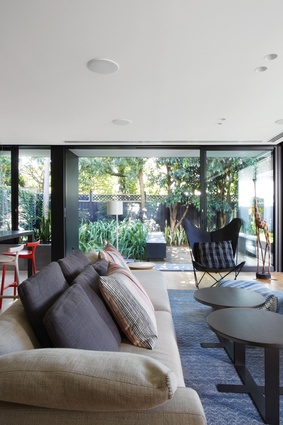 The rear living spaces open out onto a lush garden and a series of plinths surrounding a fire pit.