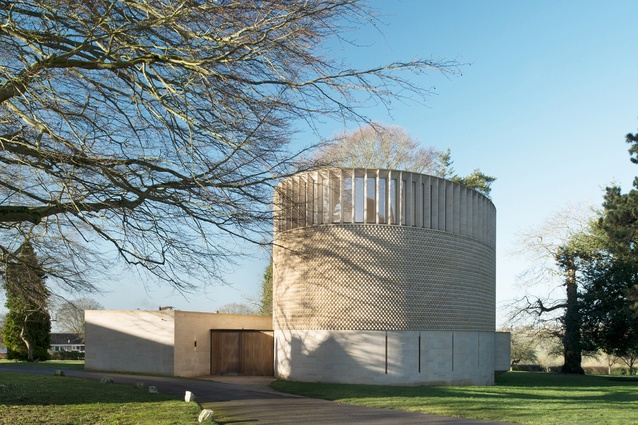 Bishop Edward King Chapel by Niall McLaughlin Architects. A circular building with a textured stone exterior topped by a wooden roof with clerestory windows that let light in.