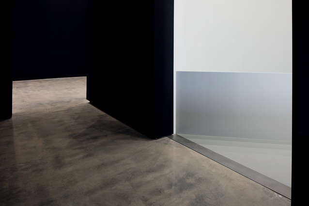 Concrete floors paired with matt black and pure white surfaces create a unified and restrained backdrop. 