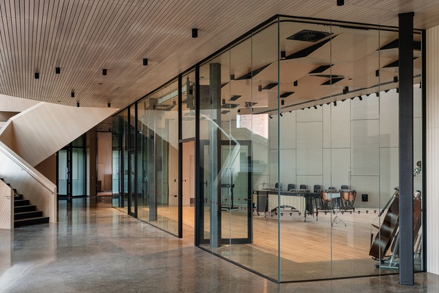 The orchestra and rock rooms face the foyer through acoustic glazing, allowing multiple musical practice events to coincide, including playing the baby grand under the stairway.