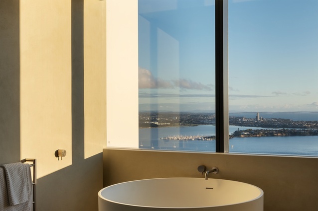 Walls in Marmorino limestone plaster and porcelain ceramic slabs on floors create a neutral backdrop for high-end bathroom fixtures and pristine bay views.